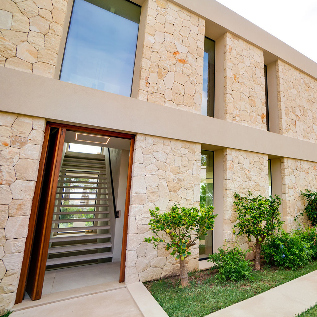 Moderner Naturstein-Eingang einer Luxusvilla auf Mallorca mit stilvoller Glasfront
